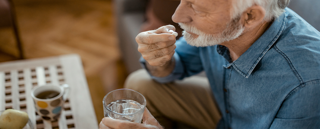 an elderly man taking a pill at home