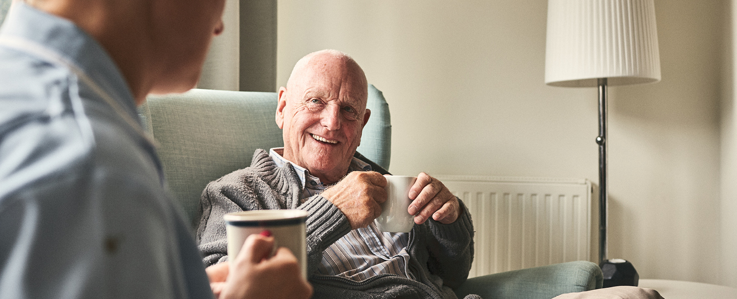 a man in an armchair talking to a healthcare professional