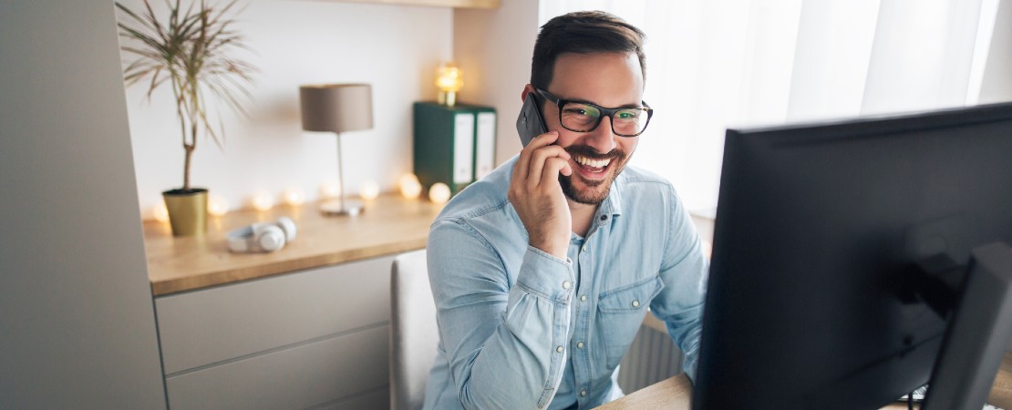 Man sitting at homedesk talking on the phone