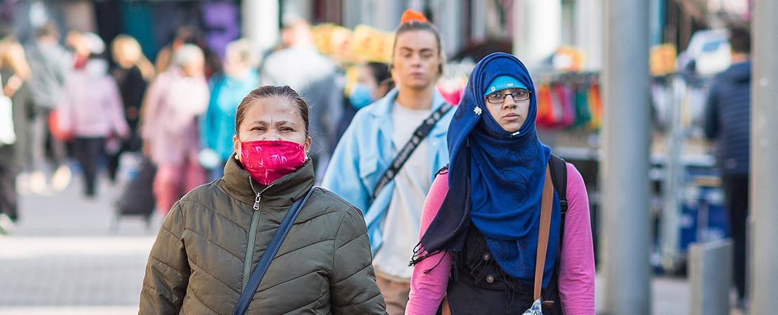 People walking down a high street one wearing a mask