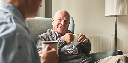 a man in an armchair talking to a healthcare professional