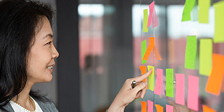 Someone looking at post-it notes on a wall in a workshop