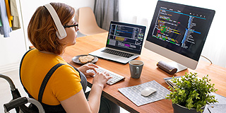 Female worker at desk in wheelchair wearing headphones